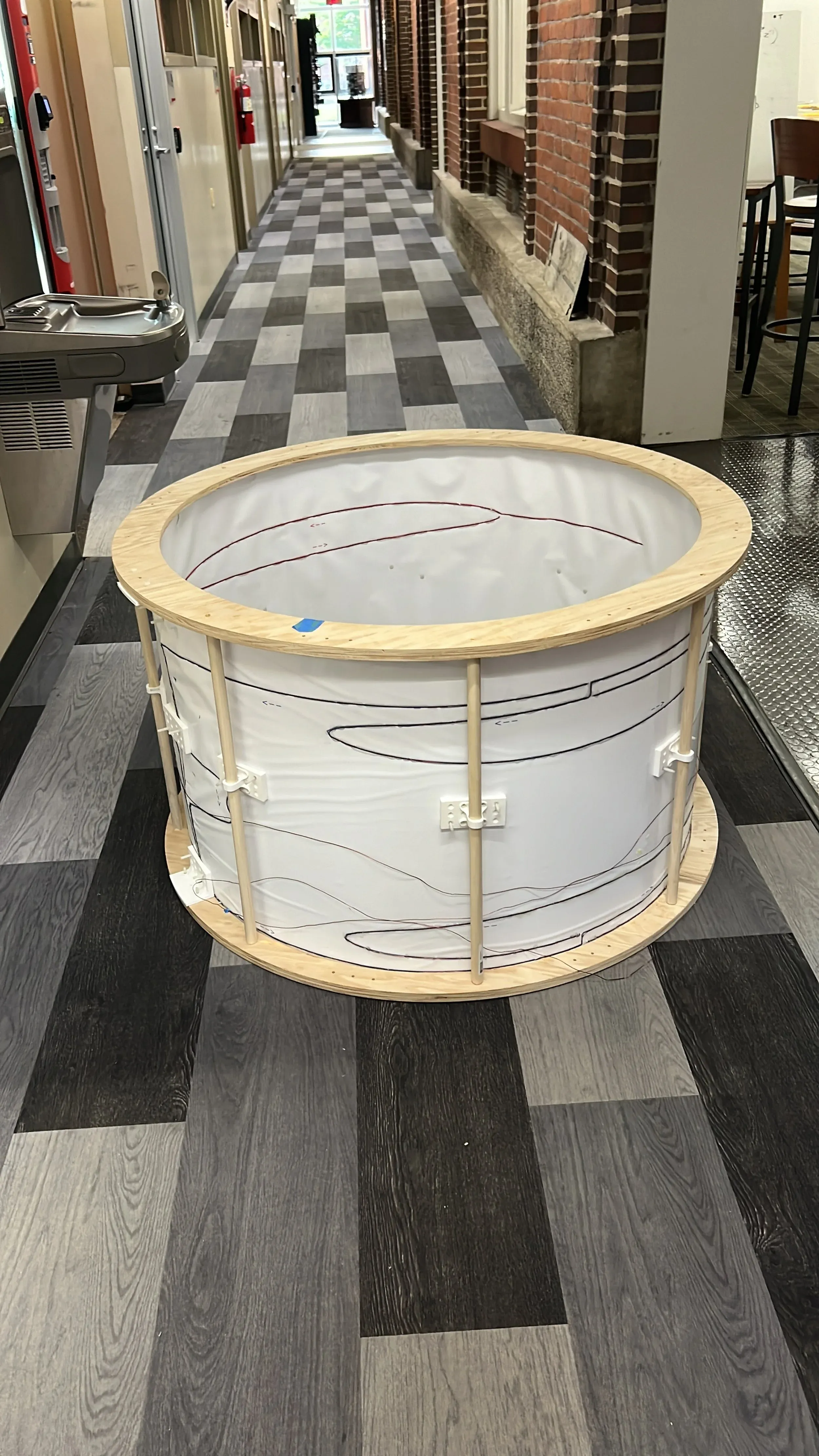 Hand-wound cylindrical coil frame being carried through a hallway