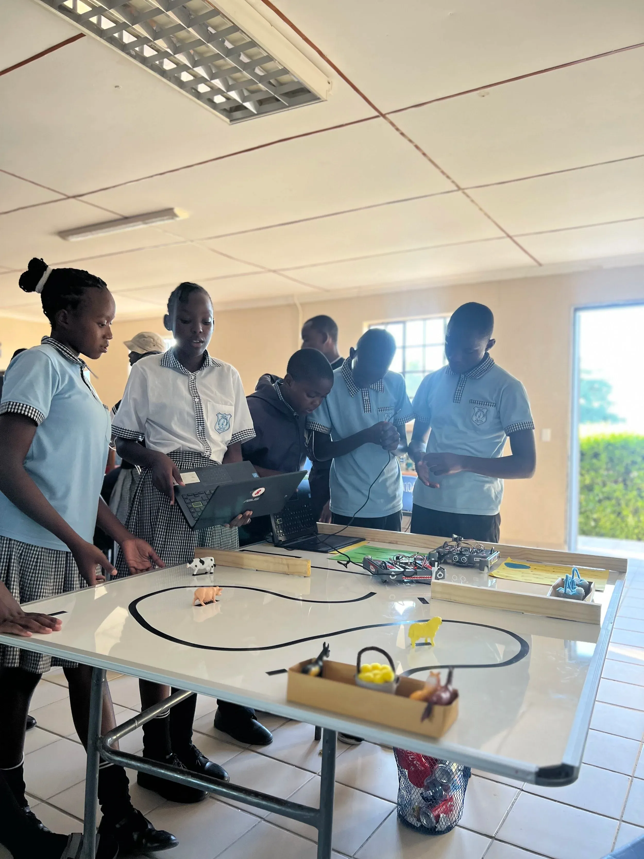 A group of students in school uniforms testing their robot on a track