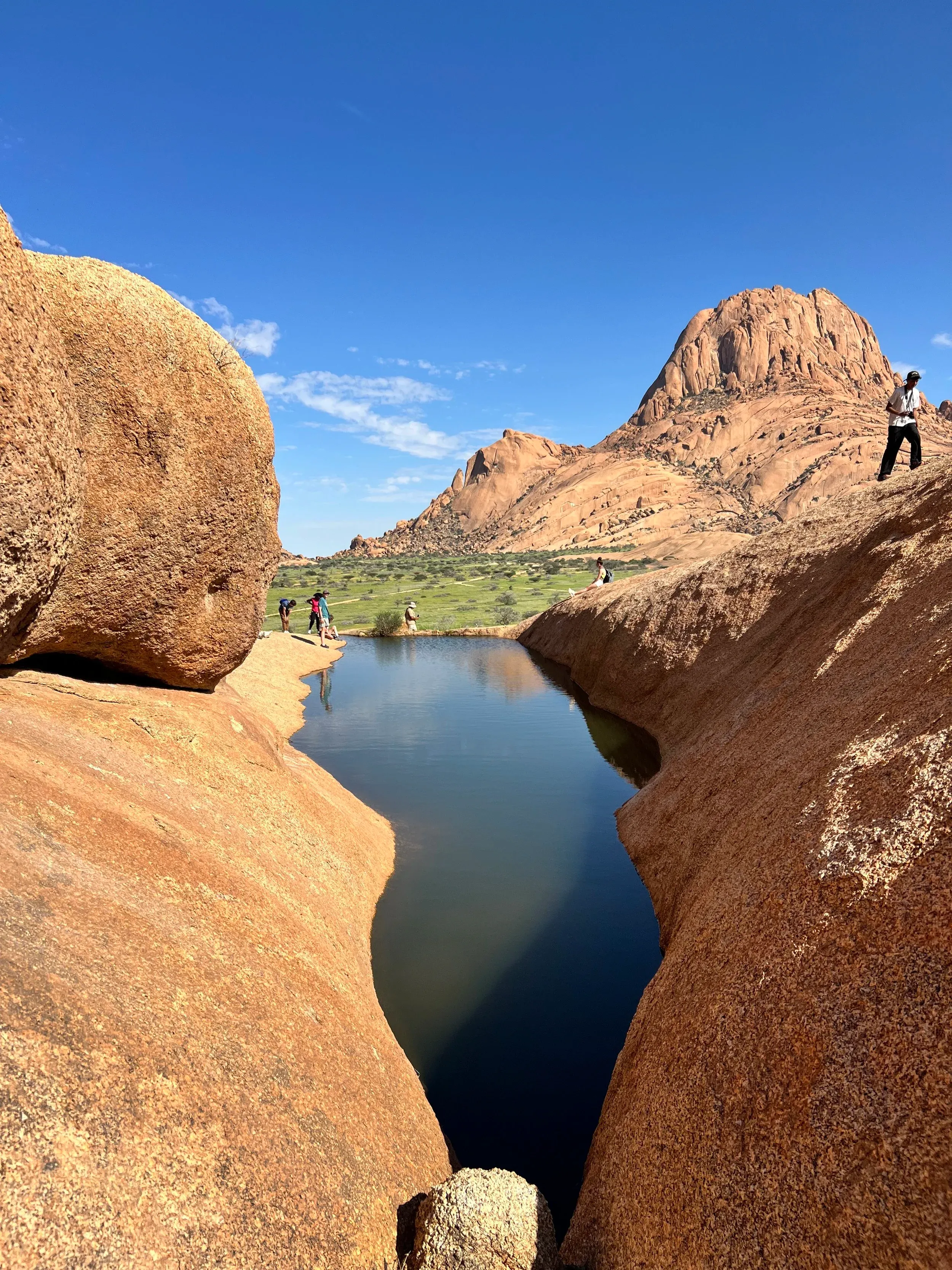 A rock pool between granite boulders under a clear sky